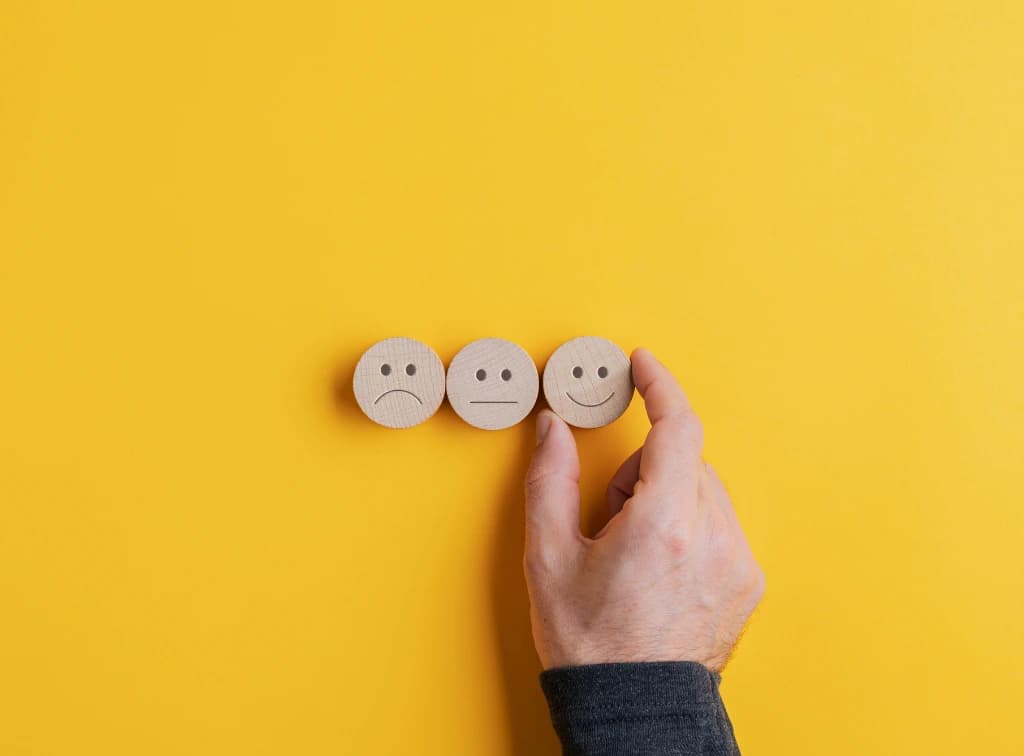 3 bonhommes en bois : un content, un neutre et un mécontent